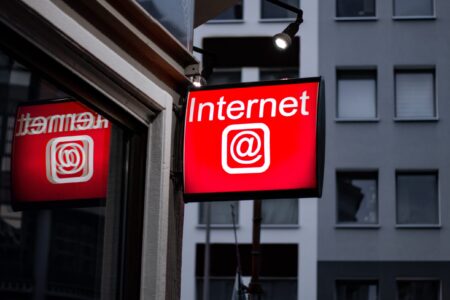 A sign written "Internet @" in a corner with a building behind.